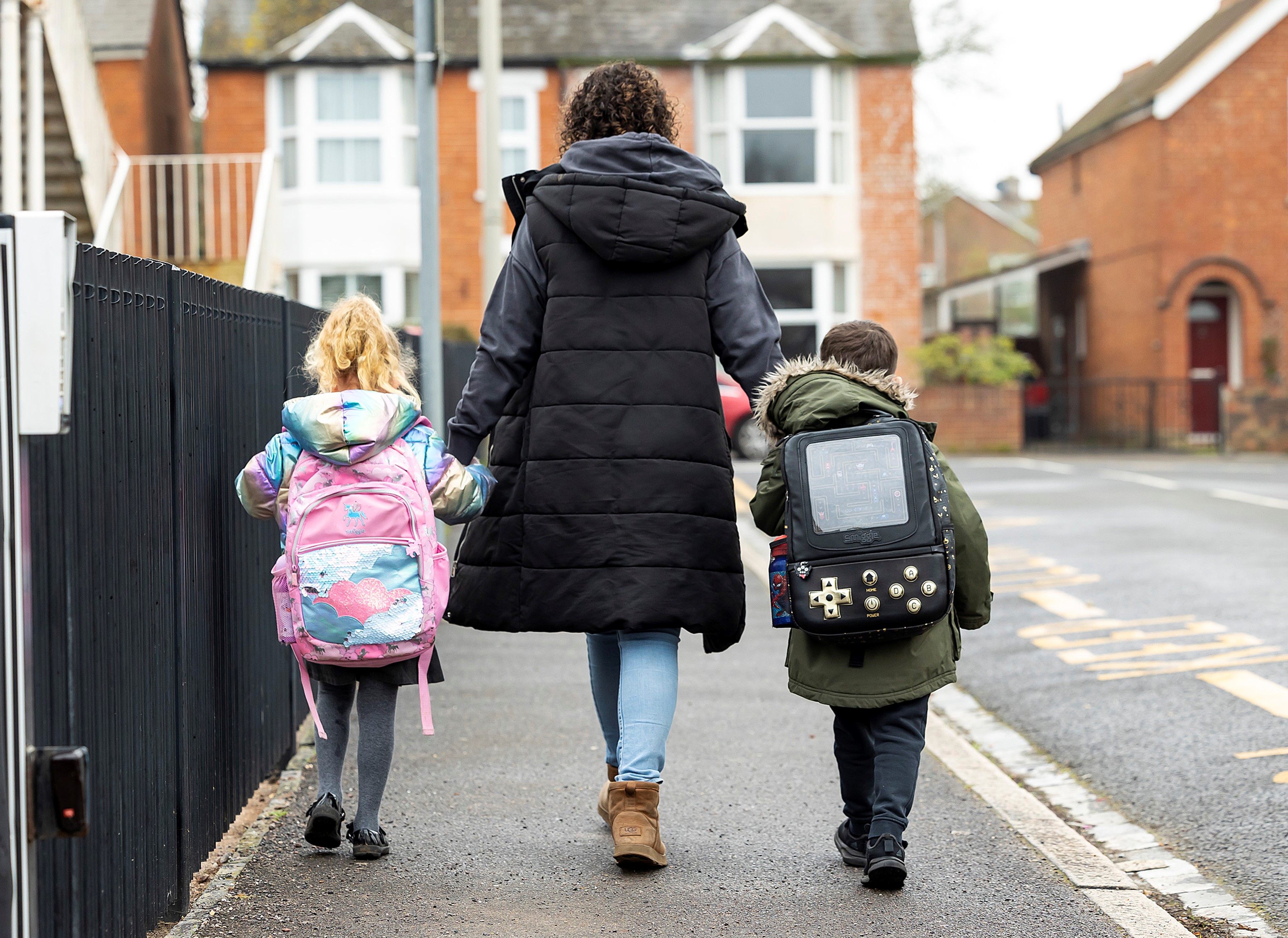 Two children and an adult walking to school.